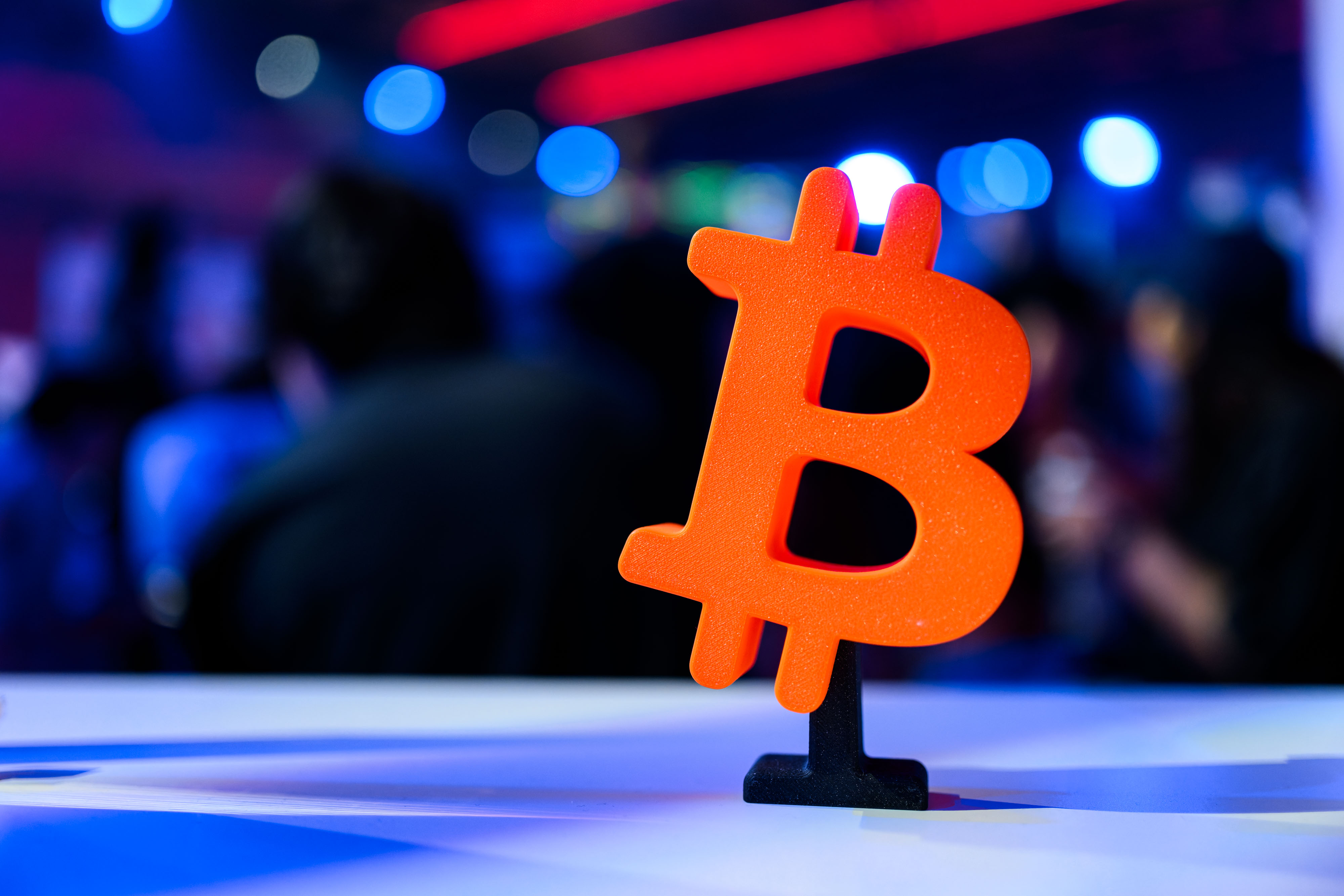 Freigestelltes 3D-gedrucktes Bitcoin-Zeichen vor unscharfem Hintergrund