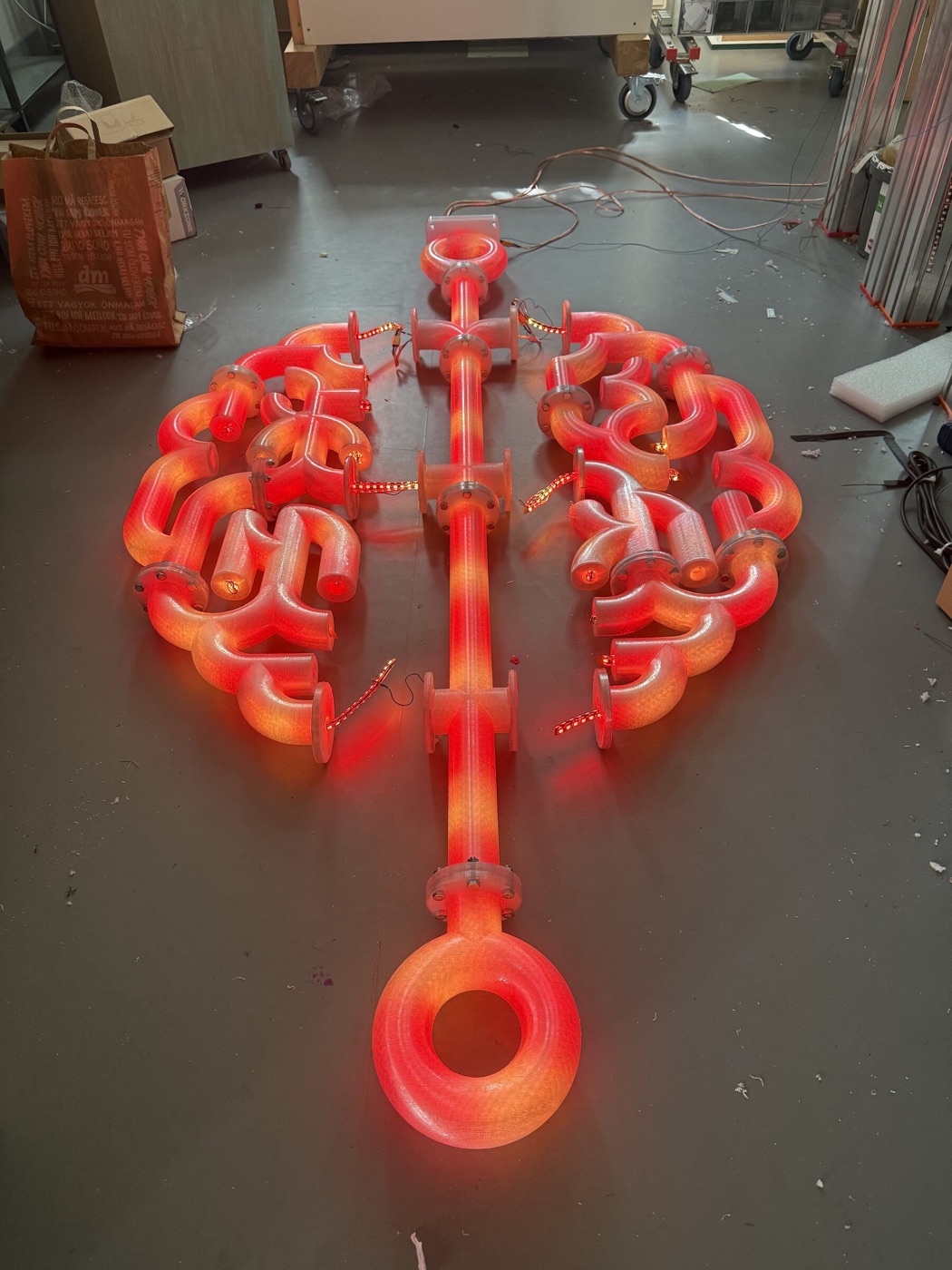 Die vollständige Hirn-Skulptur liegt rot leuchtend flach am Werkstattboden